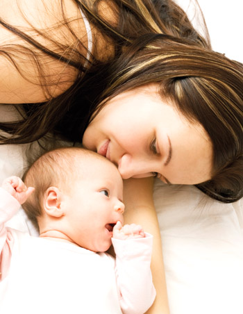 Frau mit Baby kuschelt im Bett