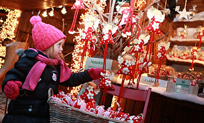 Kleines Mädchen betrachtet die Weihnachtsdekoration bei einem Marktstand am Villacher Adventmarkt