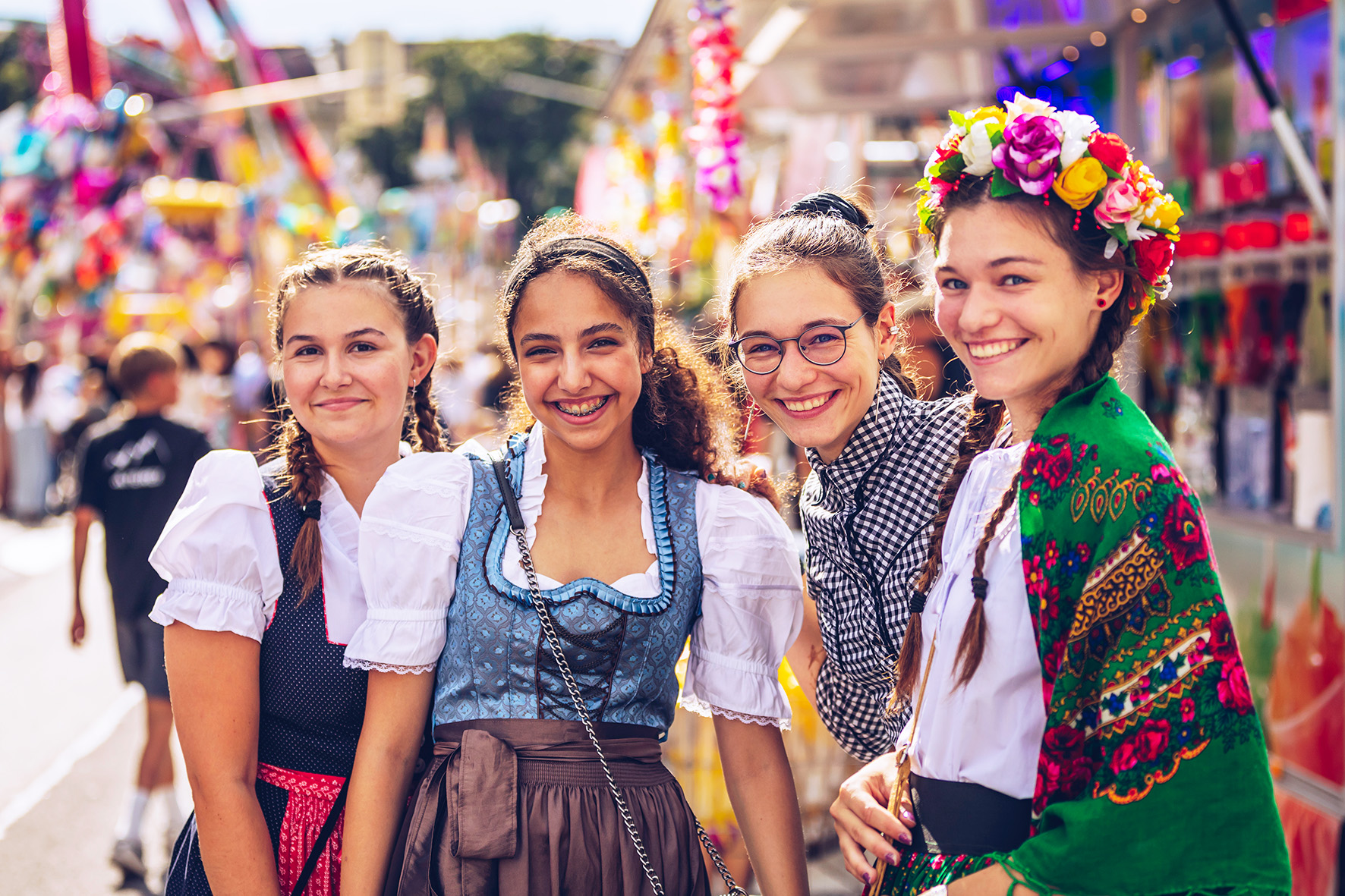 Festbesucherinnen in Tracht lächeln in die Kamera auf einem Jahrmarkt in Österreich