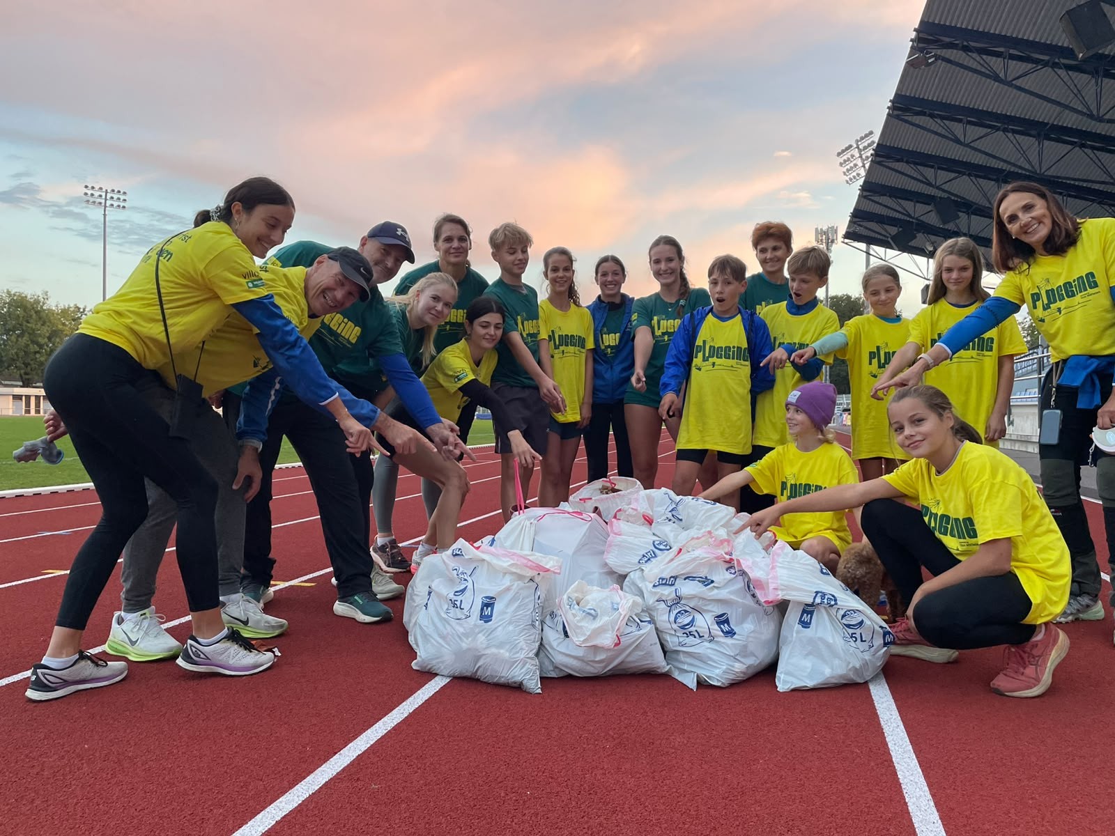 Plogging-Gruppe mit vielen Säcken Müll auf einer Laufbahn in Österreich