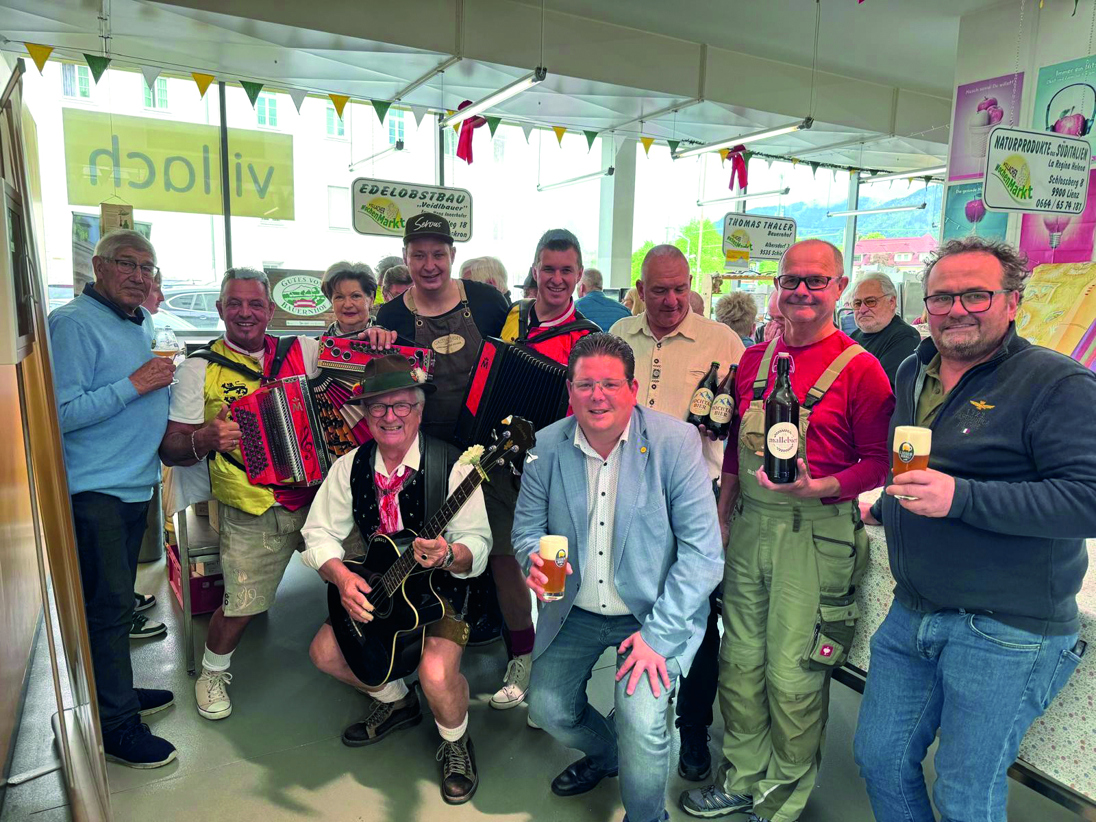 Gruppe mit Musikern und Bierflaschen in Tracht und Zivilkleidung