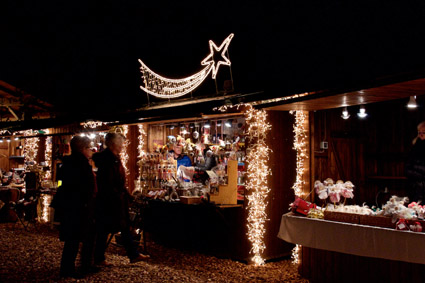 Weihnachtsstand am Adventmarkt in abendtlicher Stimmung mit Weihnachtsbeleuchtung