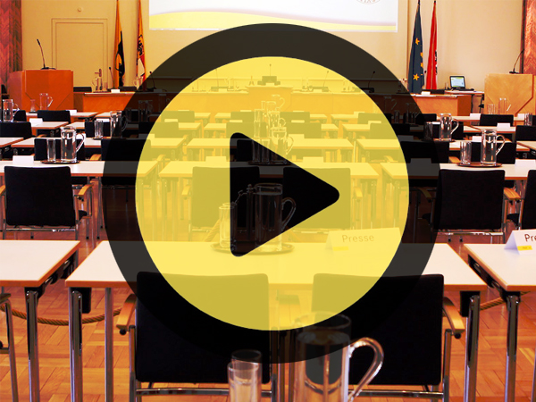 Gemeinderat von hinten, in der Mitte ein "Play" Button