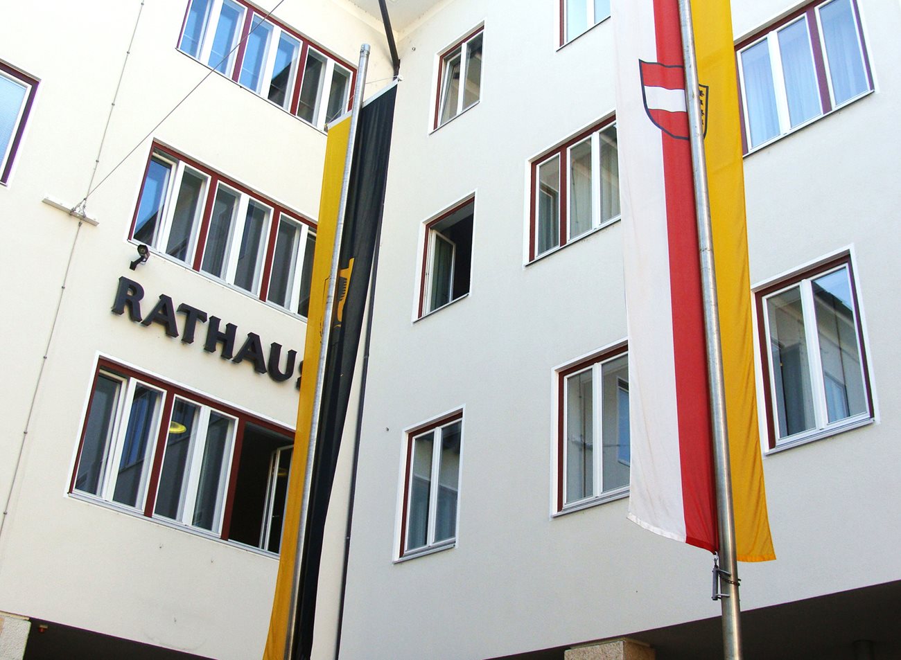 Fassade des Rathaus Villach mit der Villach-Fahne und der Kärnten-Fahne davor.