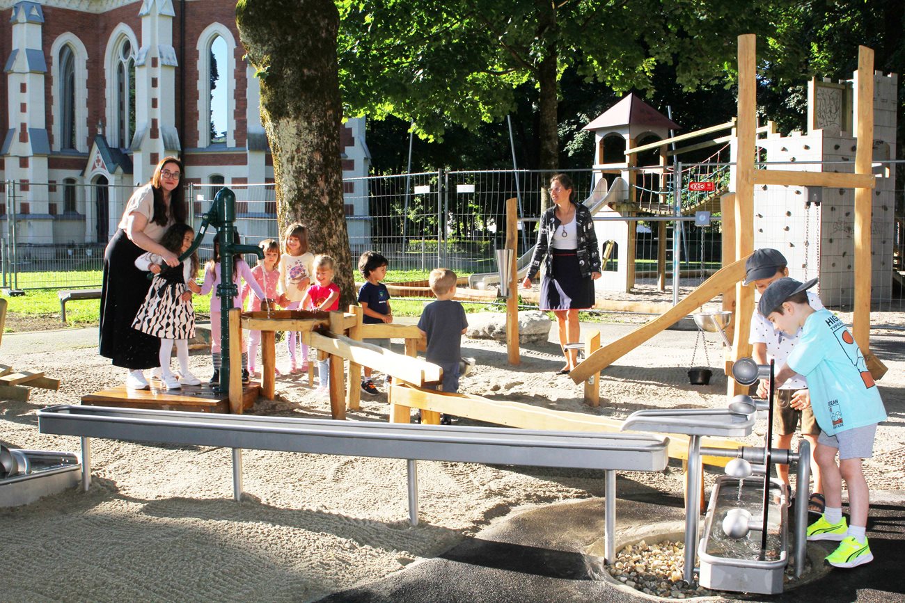 Kinder spielen auf einem Wasserspielplatz in Österreich mit zwei Betreuerinnen