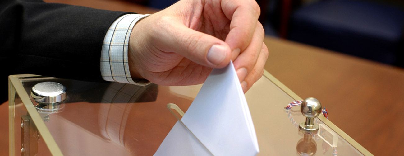 Eine Person wirft eine Wahlkarte in die Wahlurne