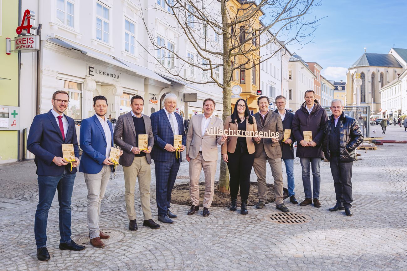 Bürgermeister Günther Albel, Vizebürgermeisterin Sarah Katholnig und Stadtrat Harald Sobe mit den Villacher Baumpaten vor dem ersten Baum auf dem Hauptplatz. 