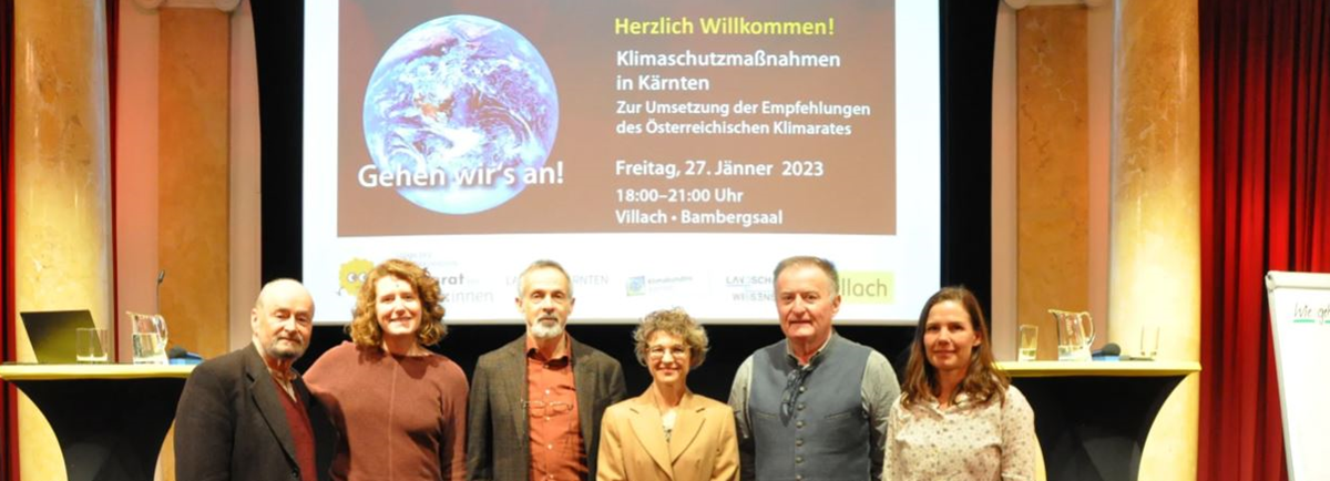 6 Menschen stehen auf einer Bühne und lachen in die Kamera